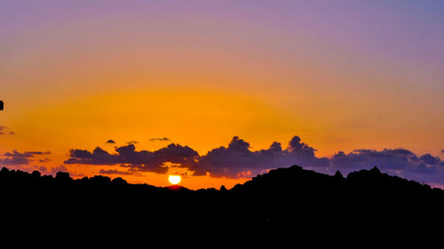 Scenic view of silhouette landscape against dramatic sky during sunset