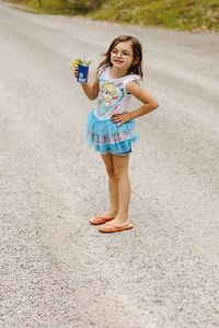 Full length of cute girl holding disposable cup on road