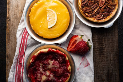 Artisan baked lemon custard tart, pecan tart, and strawberry tart on vintage style kitchen towel