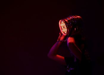 Side view of woman wearing hat against black background