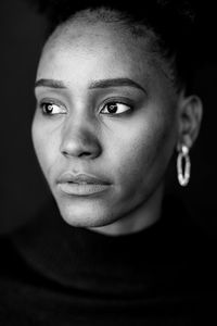 Close-up portrait of young woman against black background