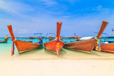 Fishing boats moored on beach against sky