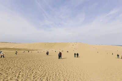 Group of people on desert against sky