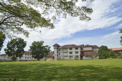 Houses on field by trees against sky