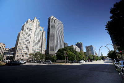 City street by modern buildings against clear sky