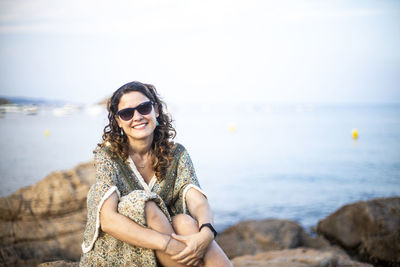 Young woman wearing sunglasses on beach against sky