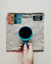 Close-up of hand holding coffee cup over white background