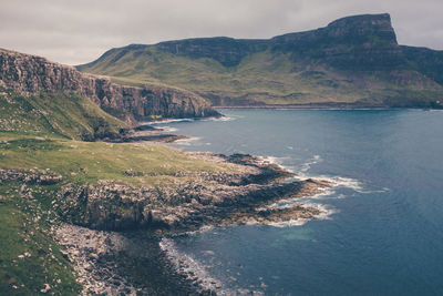 Scenic view of sea by mountains against sky