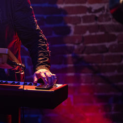 Midsection man playing piano on stage at night
