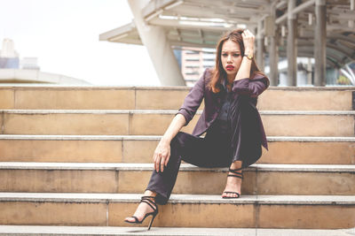 Portrait of tensed businesswoman sitting on steps in city