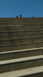 Low angle view of people on steps against clear sky