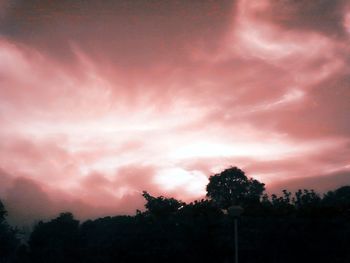 Silhouette of trees against cloudy sky