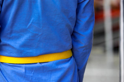 Midsection of man standing against blue wall