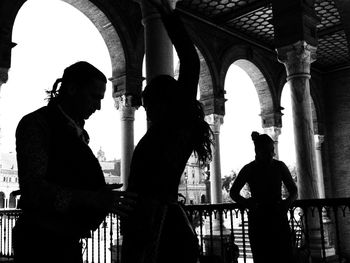 Silhouette people standing by railing