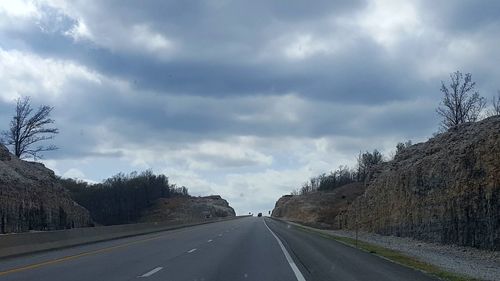 Country road against cloudy sky