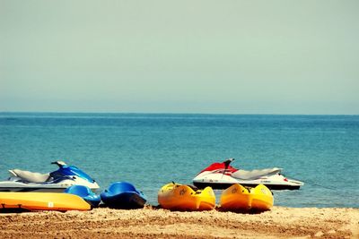 Boats moored on beach against clear sky