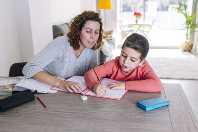 Mother assisting son in homework at home