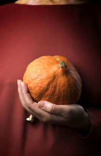 Woman in a tile-colored dress, and pumpkin in hand