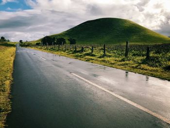 Road by field against sky