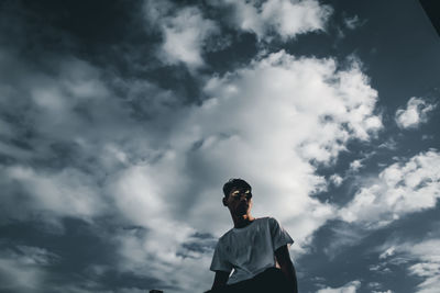 Low angle view of young man standing against sky