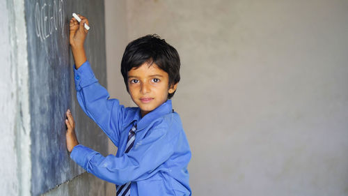 Portrait of young woman standing against wall