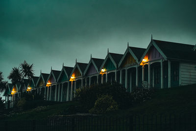 Illuminated street amidst buildings against sky at night