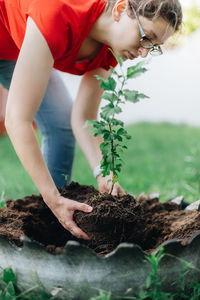 Young millennial mother  planting plants in garden being eco friendly and environmentally conscious