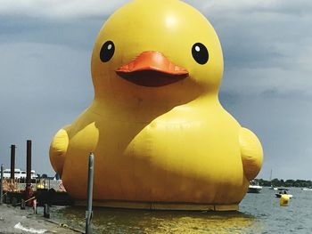 Close-up of yellow sculpture in sea against sky