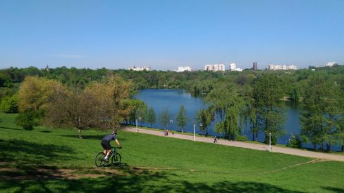 Man cycling on field against clear sky