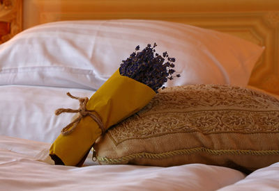 Close-up of lavenders in bouquet by cushion and pillow on bed