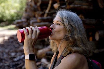 Woman with gray hair drinking water through bottle