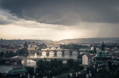 High angle view of bridge over river in city against cloudy sky