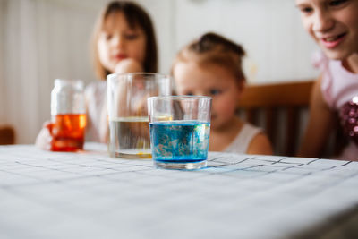 Three cute children play in the kitchen at home with colored liquids. experiments with color at home