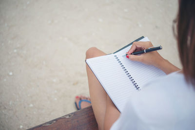 Midsection of woman writing in book 