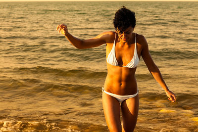 Young woman wearing bikini standing in water at beach