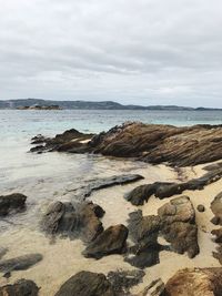 Scenic view of rocks on beach against sky