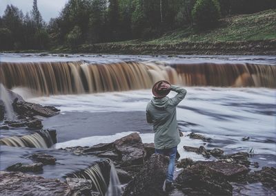 Full length of man standing against waterfall