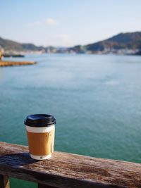 Close-up of coffee on table by sea