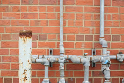 Close-up of red pipe against brick wall