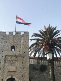 Low angle view of flag on building against sky