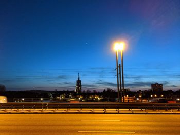 Illuminated street against sky at night