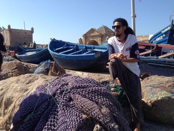 Young rasta man sitting on boat against sky