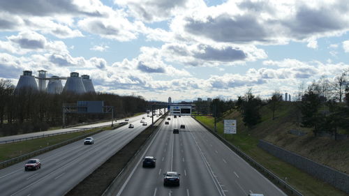 Vehicles on highway against sky in city