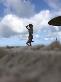 Low angle view of woman standing on beach against sky