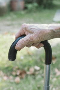 Close-up of hand holding walking cane in park