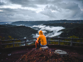 Rear view of man looking at mountain against sky