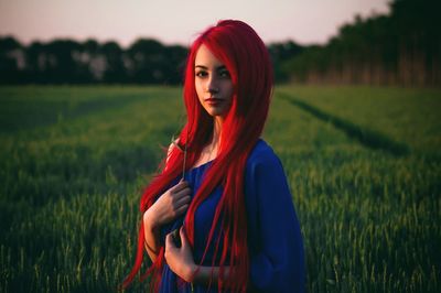 Portrait of young woman standing on grassy field