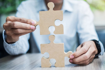 Close-up of man holding hands on table