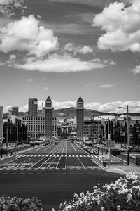 Road by buildings in city against sky