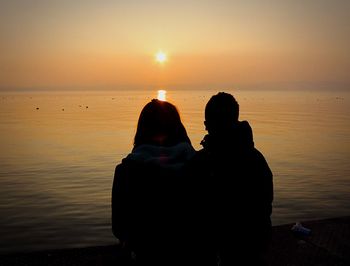 Rear view of silhouette couple at beach during sunset